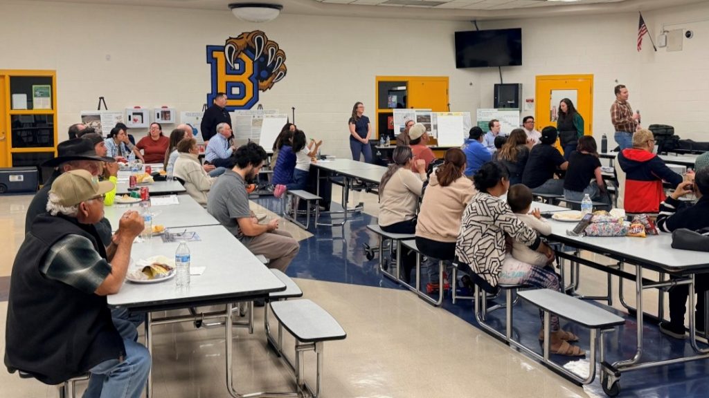  A group of residents siting down in benches looking at a presentation
